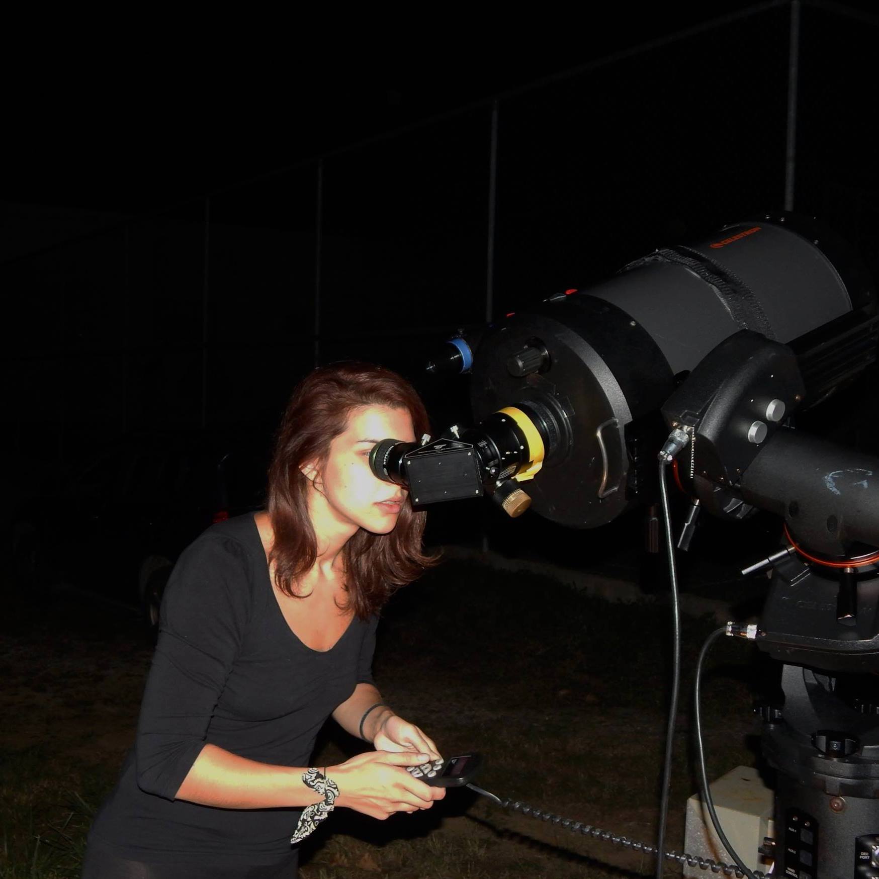 A participant looking through an observatory telescope at night.